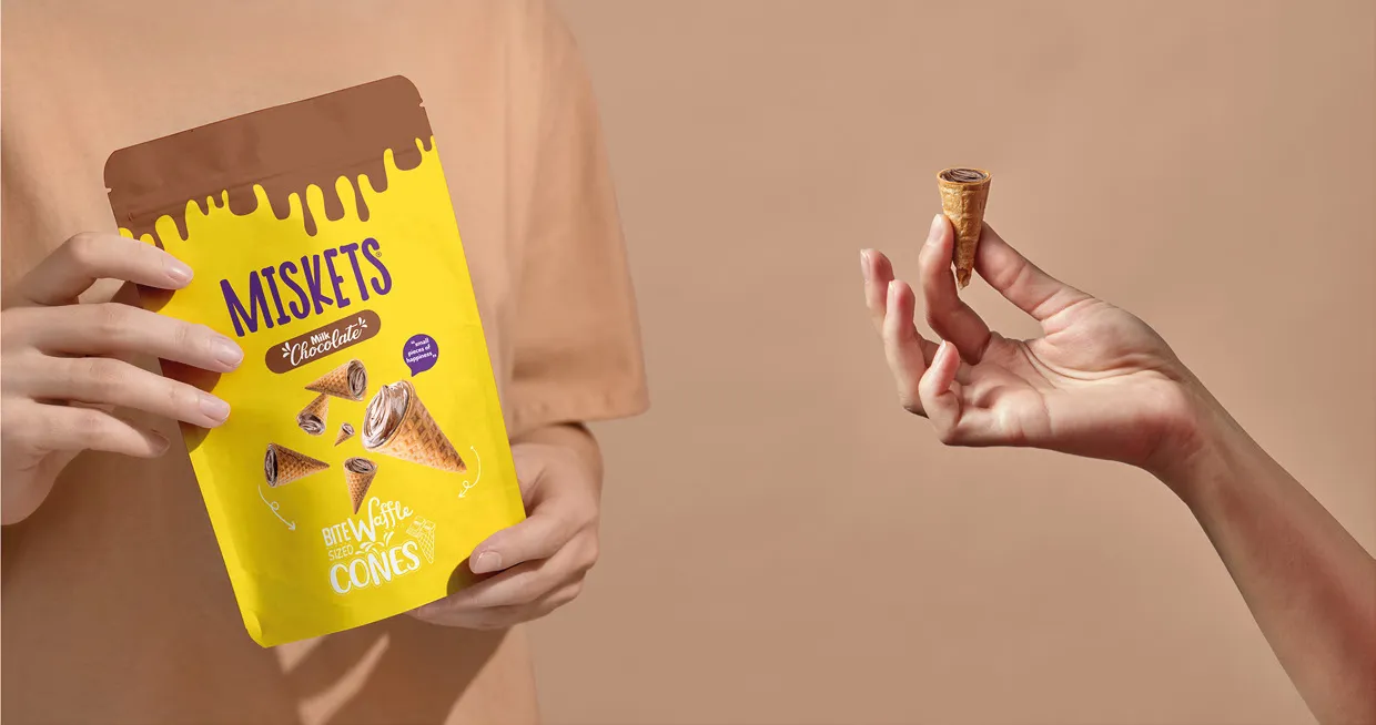 Miskets Waffle Cones ambalajını tutan eller ve parmaklar arasında küçük bir külah